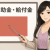 ホワイトボードの前に立つ長い黒髪の女性キャラクターが指示棒を持ち、「補助金・給付金」と書かれたボードを指し示して説明している。ビジネスカジュアルの服装で微笑んでいる。